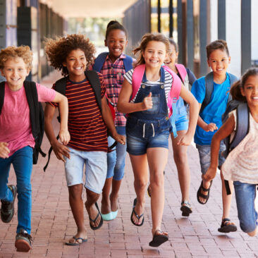School kids running in elementary school hallway, front view
